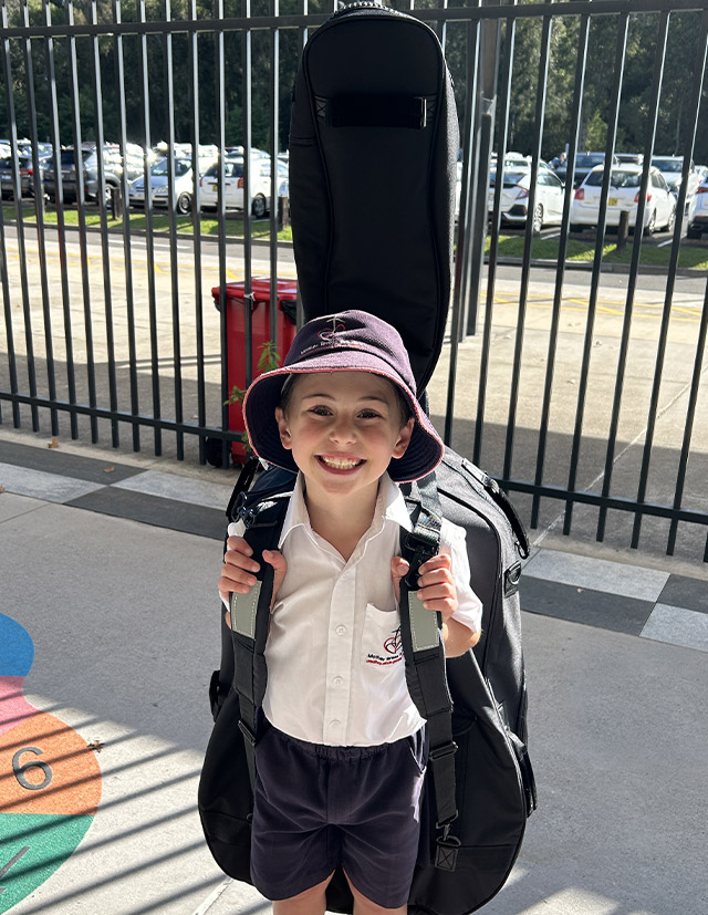 Student carrying large stringed instrument from Mother Teresa Catholic Primary School Westmead
