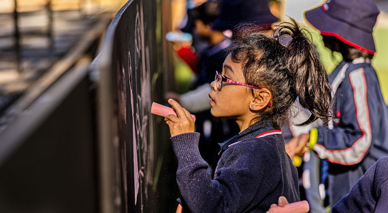 Student writing on blackboard at Mother Teresa Catholic Primary School Westmead