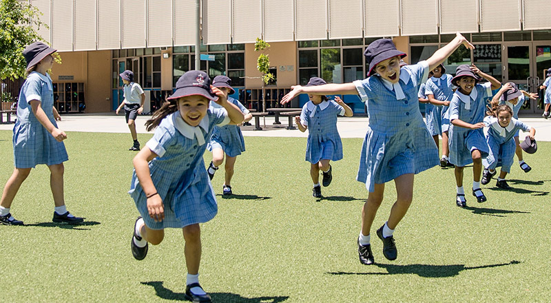 Old photo of students jumping excitedly at Mother Teresa Catholic Primary School Westmead