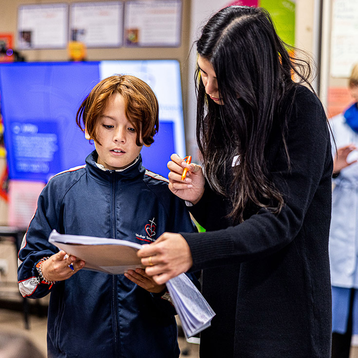 Teacher helping student at Mother Teresa Primary Westmead